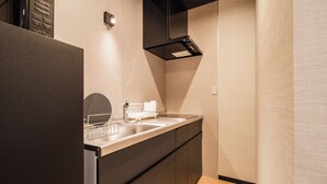 A modern kitchen with a built-in dishwasher, a stainless steel sink, and a black range hood. - BEPPU Risana (Beppu)