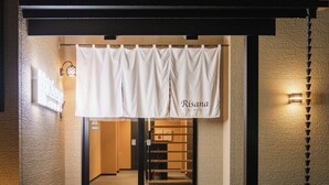 A hotel entrance with a white banner displaying the name "Risana" and a sign indicating a no-smoking area. - BEPPU Risana (Beppu)