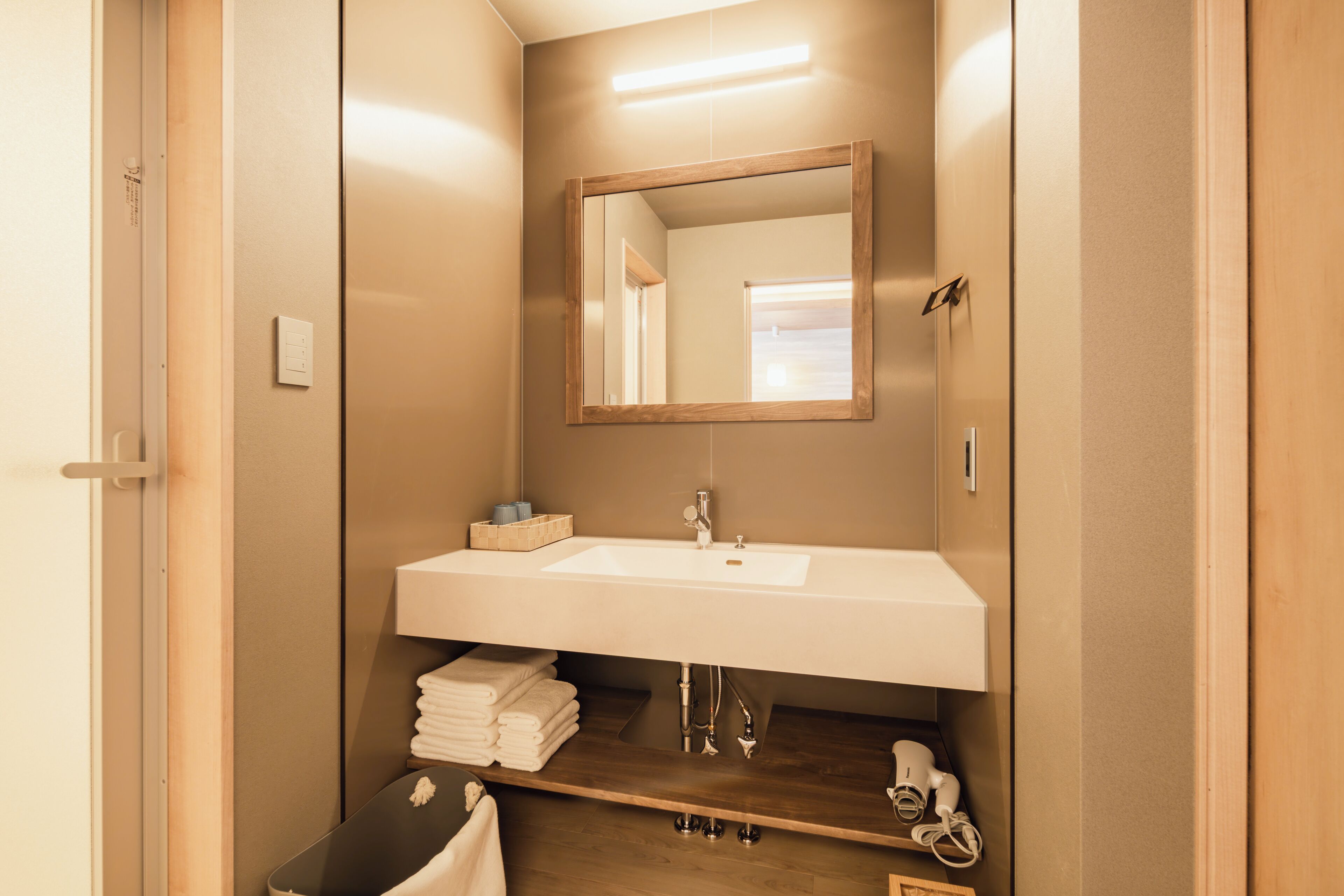 Un bagno moderno con uno specchio grande, un lavandino bianco e un mobile contenitore in legno.