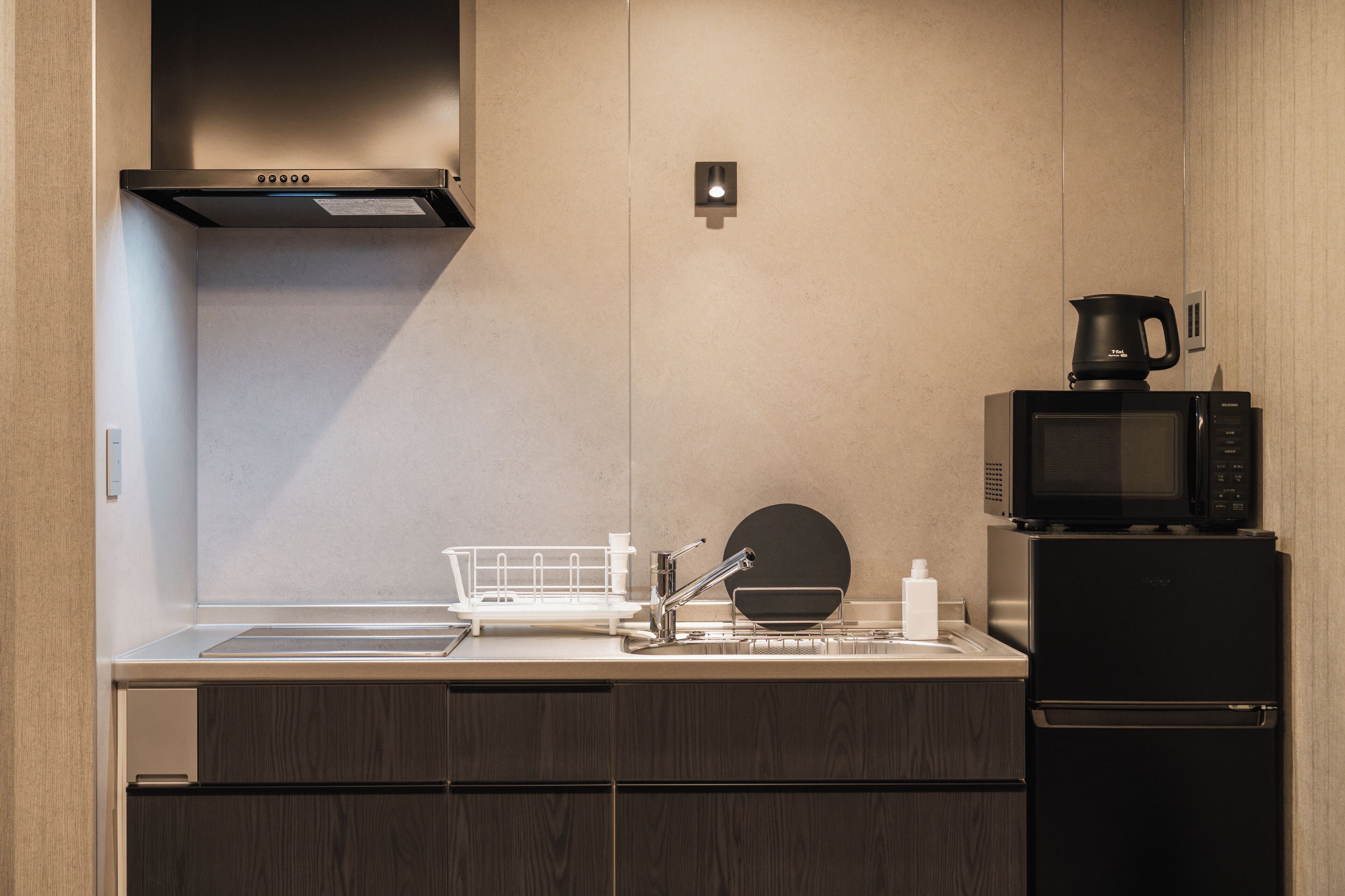 A modern kitchen with a stainless steel sink, a microwave, a coffee maker, and a built-in oven.