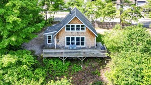 Une cabane en bois avec un toit à pignon, une véranda avec deux chaises et une vue sur les arbres environnants.