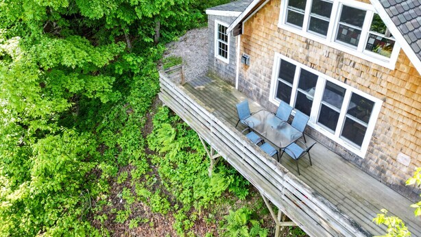 Une cabane en bois dotée d’une terrasse, entourée d’un feuillage verdoyant et luxuriant.
