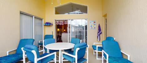 A balcony with blue chairs, a white table, and a ceiling fan.
