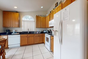 A kitchen with wooden cabinets, a white refrigerator, a stove, and a dishwasher.