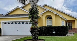 A residential house with a garage, a well-maintained lawn, and a large tree in the front yard.