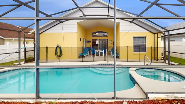 A covered swimming pool area with lounge chairs and a patio table. - 15 Min to Disney | Spacious 4BR Home w/ Pool (Kissimmee)