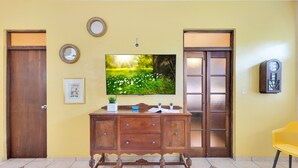 Una habitación con un armario de madera, un televisor de pantalla plana y una silla amarilla.