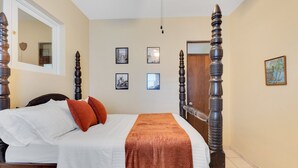Un dormitorio con cama con dosel, ropa de cama blanca y una manta marrón.