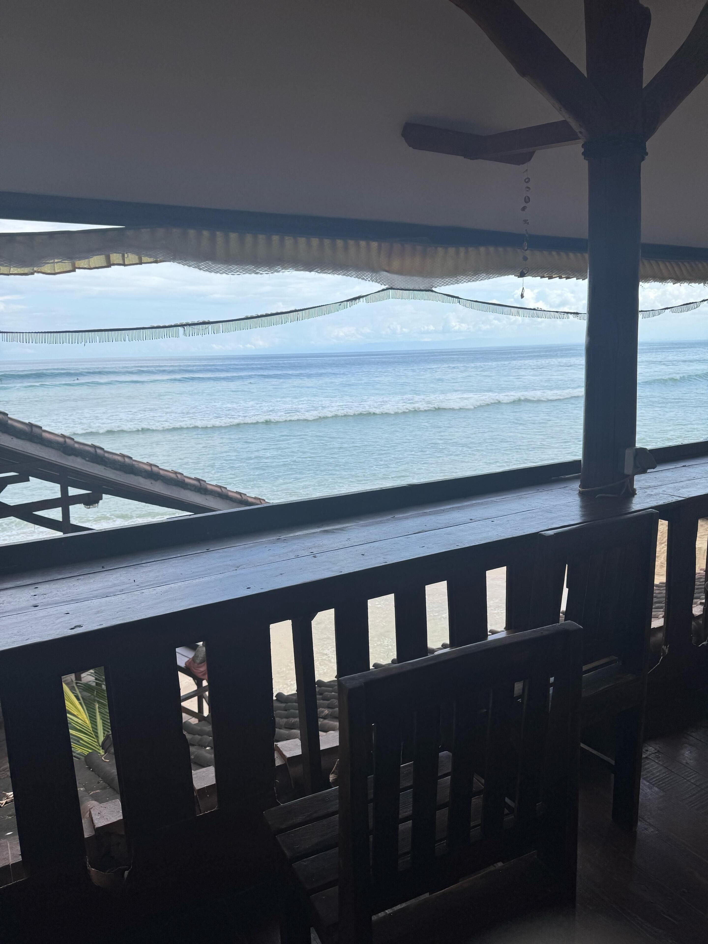 A wooden deck with a view of the ocean and a bridge in the distance.