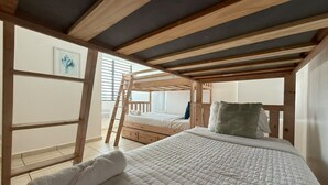 Un dormitorio con una cama litera, una escalera y una colcha blanca acolchada.