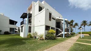 Un edificio moderno de varios pisos con techo plano, una escalera central y un césped bien cuidado.