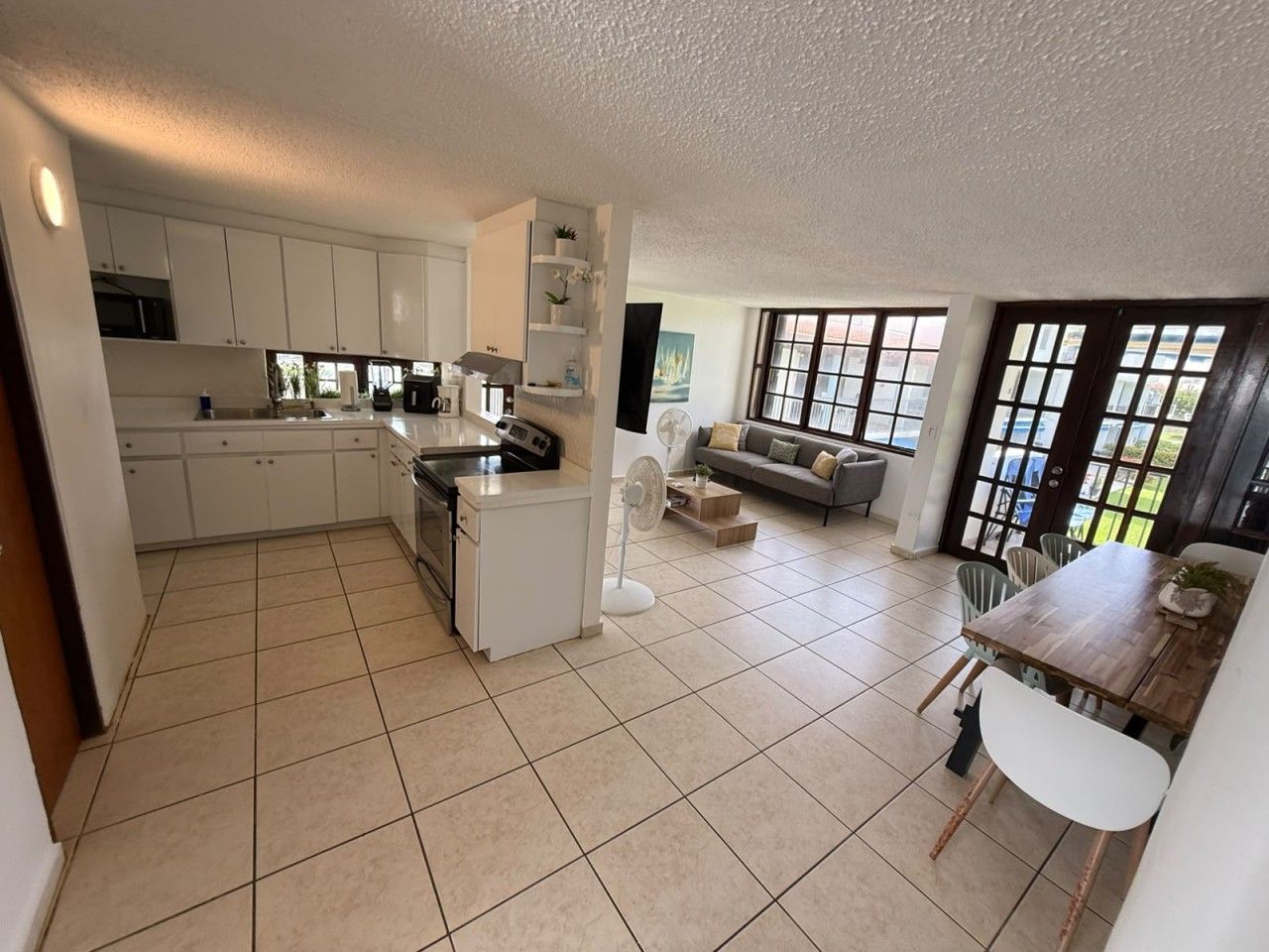 A spacious kitchen with white cabinets, a central island, and a dining area with a wooden table and chairs.