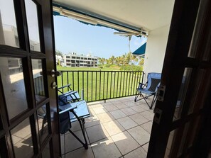 A balcony with a view of a building and a grassy area. - Playas Del Yunque | Beach Apt W/Pool In Rio Geande (Río Grande)