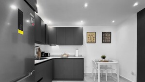 Una cocina moderna con muebles oscuros, encimera blanca y suelo de mármol.