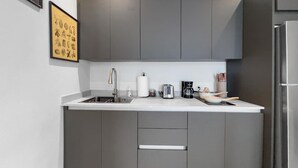 Una cucina moderna con mobili grigi, un frigorifero in acciaio inossidabile, un lavello e una macchina per il caffè.