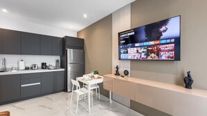 Una cucina moderna con TV integrata, tavolo da pranzo bianco e mobili grigi.