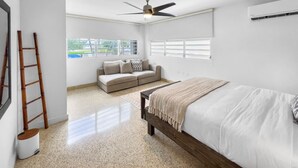 Une chambre à coucher avec un lit, un ventilateur de plafond, une fenêtre et un canapé.