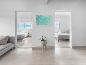 Une chambre d’hôtel spacieuse et moderne, dotée d’un grand lit, d’un petit coin salon et offrant une vue sur la mer par les fenêtres.