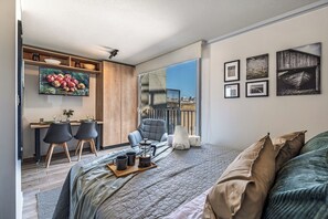 A modern bedroom with a large bed, a desk with chairs, and a balcony with a city view. - Top Studio*Modern 1D 1B*2PAX*UCatolica Metro*Bustamante Metro (Santiago)