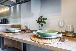 A modern kitchen with a wooden countertop, a green bowl, wine glasses, and a vase with flowers. - Top Studio*Modern 1D 1B*2PAX*UCatolica Metro*Bustamante Metro (Santiago)