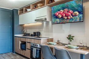 A modern kitchen with built-in appliances, a dining area with a table set for two, and a painting of apples on the wall. - Top Studio*Modern 1D 1B*2PAX*UCatolica Metro*Bustamante Metro (Santiago)