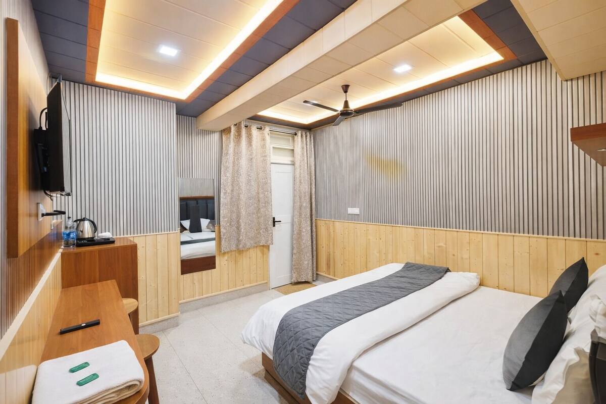 A hotel room with a bed, a desk, a chair, a television, and a ceiling fan.