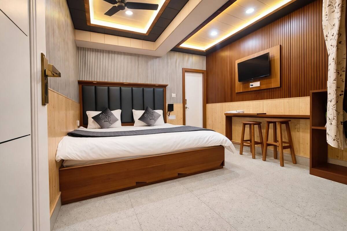 A modern bedroom with a bed, a desk, and a TV.