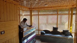 A wooden interior with a reception desk, a sofa, and a lattice partition. - Hotel Gulistan (Srinagar)