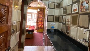 A kitchen with wooden cabinets, a black countertop, and a stainless steel sink. - Hotel Gulistan (Srinagar)