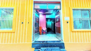 A yellow building with a central entrance, a staircase leading up, and a hallway inside. - Shri Raghav Kunj 200 Mtr from RAM Temple (Faizabad)
