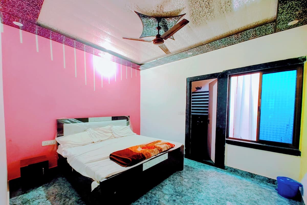 A bedroom with a bed, a ceiling fan, a window, and a door.