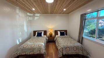 Een kamer met twee bedden, een houten plafond en een raam met uitzicht.