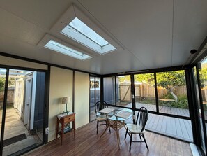 A sunroom with a glass table and chairs, a lamp, and a view of the backyard.