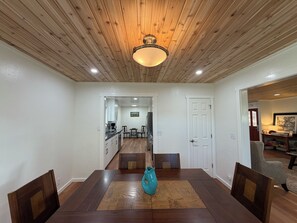 A dining area with a wooden ceiling, a central table, and chairs.