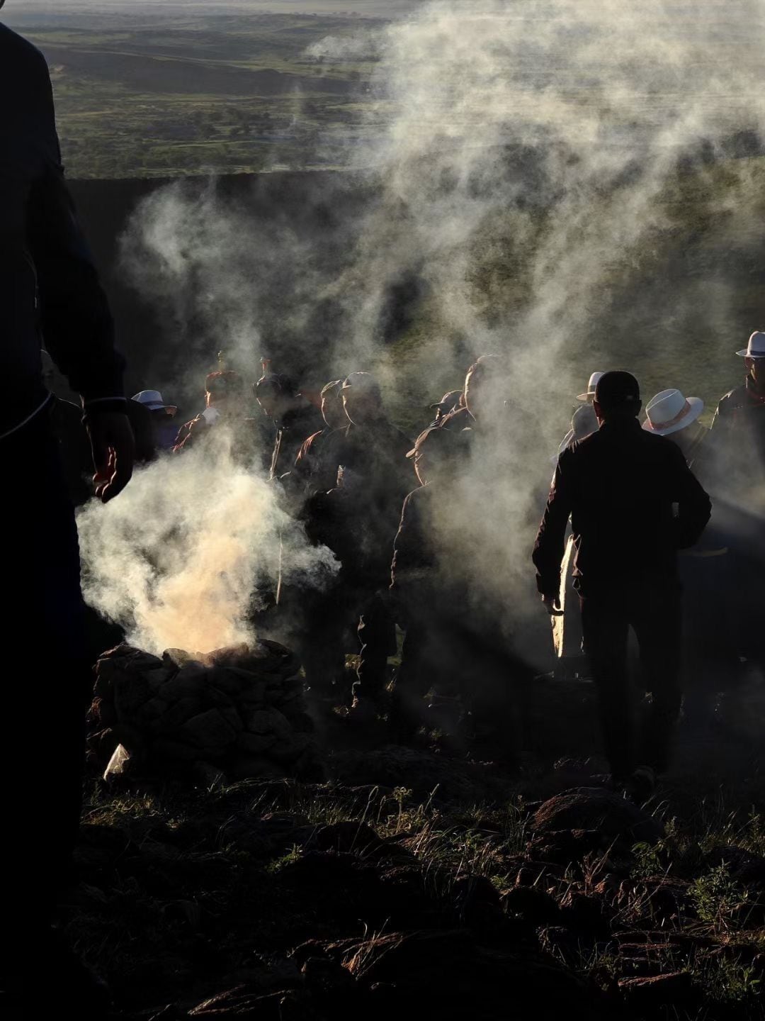 A group of people in a natural setting with smoke or mist, possibly indicating an outdoor activity or event.