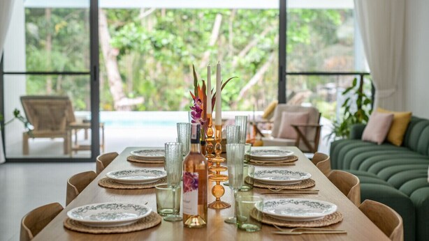 A dining table set with plates, glasses, and a centerpiece with candles and flowers. - Zen Paradise Pool Villa by Sea N' Rent (Ko Pha-ngan)