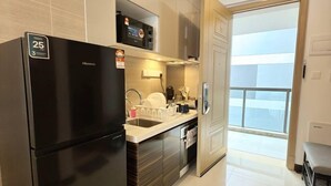 Eine moderne Küche mit einem schwarzen Kühlschrank, Edelstahlgeräten und einem großen Fenster mit Blick auf den Balkon.