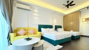 Ein modernes Hotelzimmer mit einem gelben Sofa, zwei Betten, einem runden weißen Couchtisch und einem Deckenventilator.