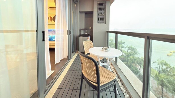 Ein Balkon mit Korbstühlen und einem kleinen Tisch, mit Blick auf eine reizvolle Landschaft.