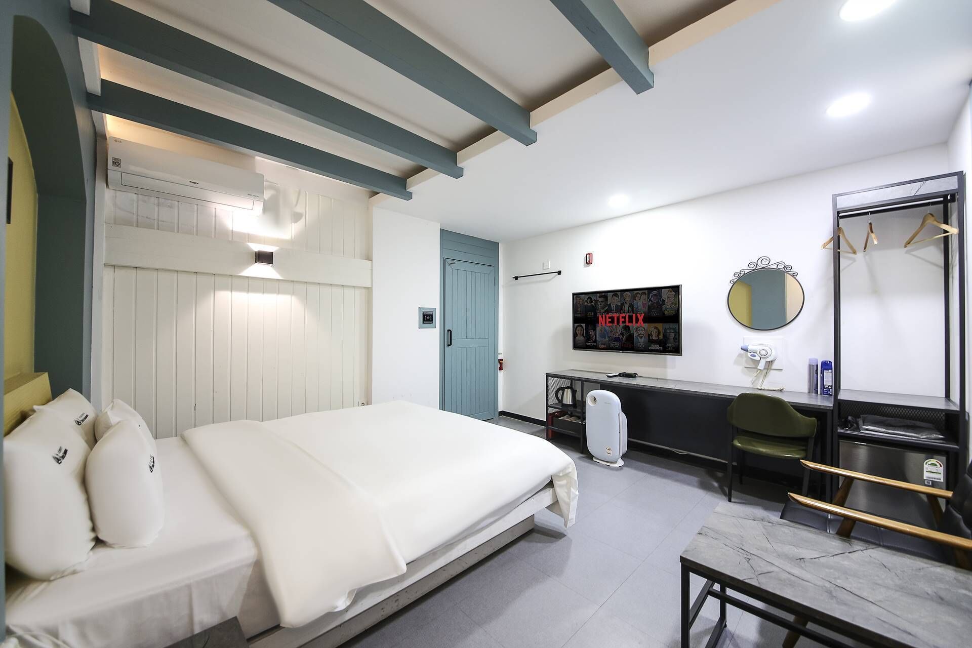 Una camera d'albergo moderna con un letto, una scrivania, una televisione, uno specchio e un armadio.