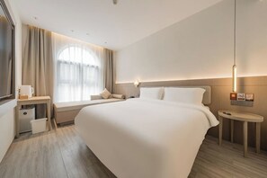 A hotel room with a large bed, a bedside table, a nightstand, a window with curtains, and a wall-mounted light fixture. - 18HOW Qianmen Grape Courtyard Hotel (Beijing)
