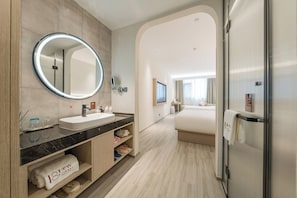Ein modernes Hotelbad mit einem großen Spiegel, einem Waschbecken und einer Duschkabine.