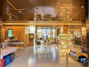 A spacious lobby with a reception desk, a seating area, and a display of products. - 18HOW Qianmen Grape Courtyard Hotel (Beijing)