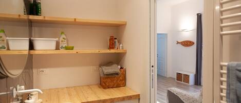 Ein Badezimmer mit einem Holzkosmetikschrank, einem weißen Waschbecken und Regalen mit Pflegeprodukten.
