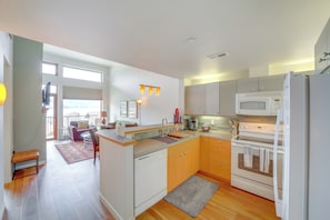 Cocina moderna equipada con lavavajillas, horno y microondas. Cuenta con una zona de comedor con banco y alfombra.