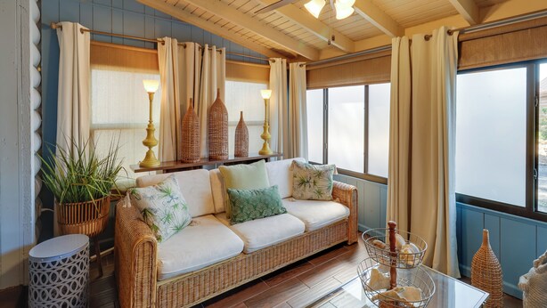 A wicker sofa with cushions, a round side table, wicker baskets, and a ceiling fan. - Fish On-Site: Okeechobee Cabin w/ Pool Access (Okeechobee)