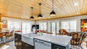 Una cocina moderna con isla central, armarios oscuros e iluminación colgante.