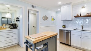 Una cocina moderna con armarios blancos, electrodomésticos de acero inoxidable y una encimera de madera.