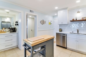 A modern kitchen with white cabinets, stainless steel appliances, and a wooden countertop. - Beachfront Abode w/ Pool Access in Gulf Shores! (Gulf Shores)