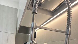 Una cocina de acero inoxidable con un grifo moderno y una cafetera.